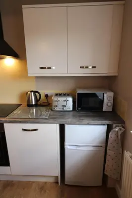 a kitchen with white cabinets and a counter with a microwave at Blairmains Guest House in Kirk of Shotts