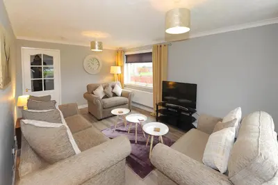 a living room with a couch and a tv at Three Bedroom Spacious House in Stirling