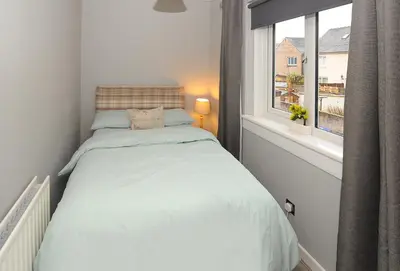 a small bedroom with a bed and a window at Three Bedroom Spacious House in Stirling