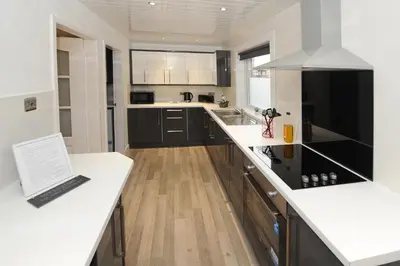 a kitchen with white counters and a laptop on a counter at Three Bedroom Spacious House in Stirling