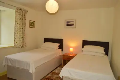 two beds in a bedroom with a candle on a table at Gorsnavoon Cottage in Clachaig