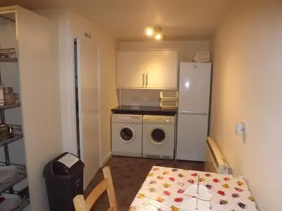 a kitchen with a table and a white refrigerator at Gorsnavoon Cottage in Clachaig