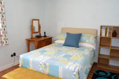 a bedroom with a bed and a dresser and a mirror at Gorsnavoon Cottage in Clachaig