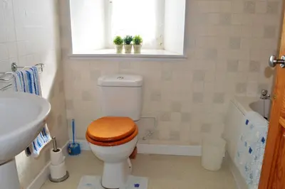 a bathroom with a toilet with a wooden toilet seat at Gorsnavoon Cottage in Clachaig