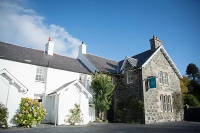 an old stone house with flowers in front of it at Bridgend Hotel in Bridgend