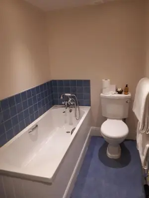 a bathroom with a tub and a toilet and blue tiles at Bridgend Hotel in Bridgend