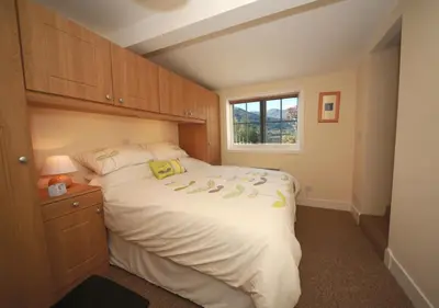 a bedroom with a large white bed with a window at Ivybank Cottage in Lochgoilhead
