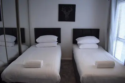 two beds in a room with white sheets and pillows at 3 Bedroom-Kelpies Serviced Apartments Burns in Falkirk