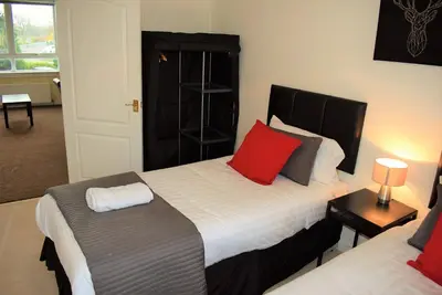 a bedroom with two beds with red pillows at Kelpies Serviced Apartments MacGregor- 2 Bedrooms in Grangemouth