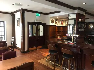 a bar in a pub with wooden floors and chairs at Rab Ha's in Glasgow