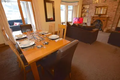 a dining room with a wooden table with wine glasses at Ashburn Cottage in Lochgoilhead
