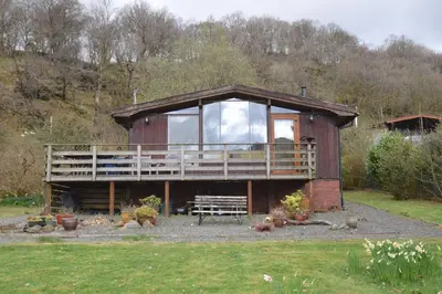 a large wooden house with a large balcony at Dalriada by Loch Goil in Carrick