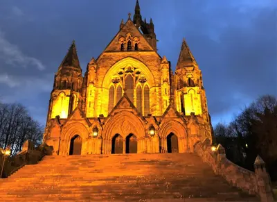 an old church with lights on it at night at Castle Gait, Paisley in Paisley