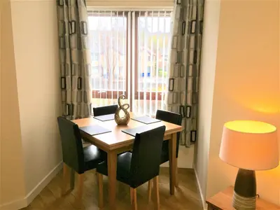 a dining room table with chairs and a window at Castle Gait, Paisley in Paisley