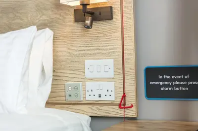 a bedroom with a bed and a light switch and a sign at The Raven’s Cliff Lodge by Marston's Inns in Motherwell