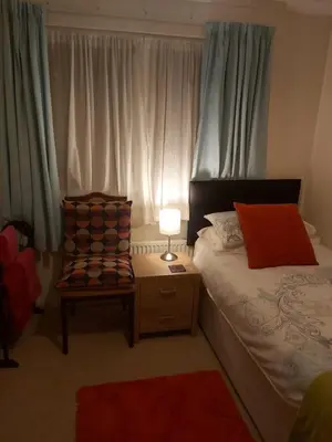 a bedroom with a bed and a chair and a lamp at Homely Haven, Dunfermline in Dunfermline