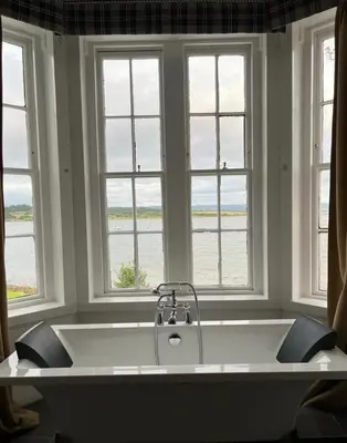 a large white tub in a room with windows at The Grey Gull Hotel in Ardrishaig