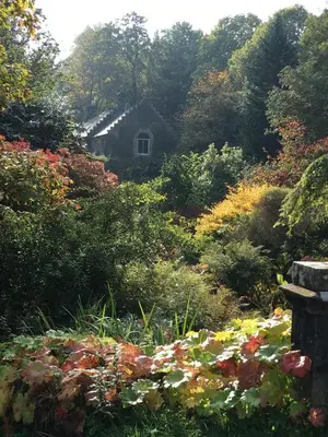 a garden with flowers and a house in the background at Finlaystone Barns in Port Glasgow