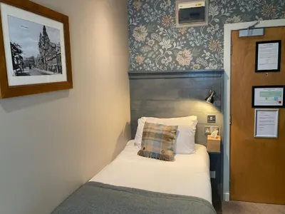a small bedroom with a bed and a picture on the wall at West Port Hotel in Linlithgow