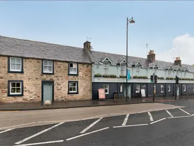 an old brick building on the corner of a street at West Port Hotel in Linlithgow
