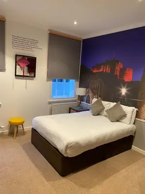 a bedroom with a large bed with a painting on the wall at Stewart by Heeton Concept - Aparthotel Edinburgh in Edinburgh