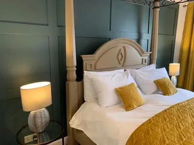 a bedroom with a bed with white sheets and yellow pillows at Lamlash Bay Hotel in Lamlash