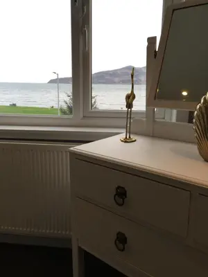 a dresser with a view of the ocean from a window at Lamlash Bay Hotel in Lamlash