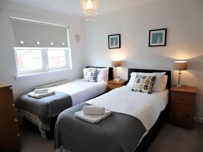 a bedroom with two beds and a window at Signature - Brambling House in Coatbridge