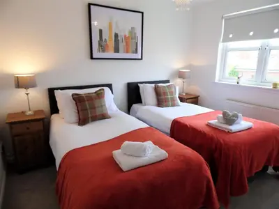 two beds in a room with red sheets and towels at Signature - Brambling House in Coatbridge