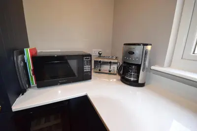 a kitchen counter with a microwave and a coffee maker at Crann Mhor Holiday Home in Lochgoilhead