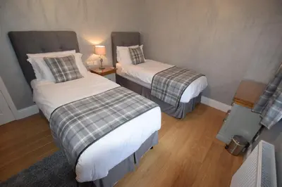a room with two beds and a lamp on a floor at Crann Mhor Holiday Home in Lochgoilhead
