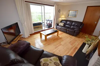 a living room with a leather couch and a television at Cobbler View No. 1 in Lochgoilhead