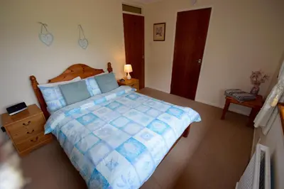 a bedroom with a large bed with a blue comforter at Cobbler View No. 1 in Lochgoilhead