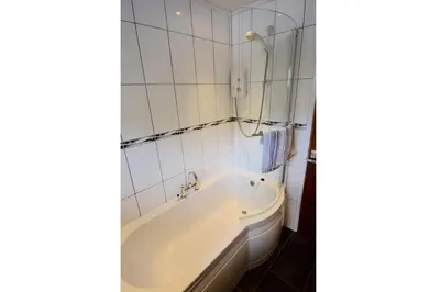 a bath tub in a bathroom with white tiles at Cobbler View No. 1 in Lochgoilhead