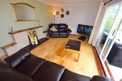 a living room with a leather couch and a fireplace at Cobbler View No. 1 in Lochgoilhead