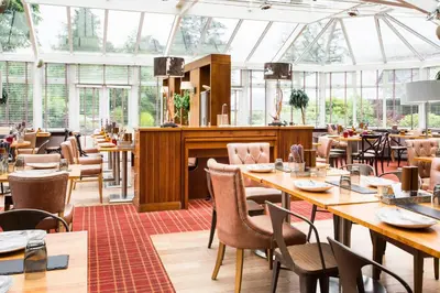 a restaurant with wooden tables and chairs and windows at Auchrannie Resort in Brodick