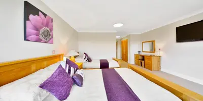 a hotel room with two beds and a flat screen tv at Peggyslea Farm B&B in Edinburgh