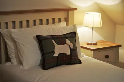 a bedroom with a bed with a pillow on it at The Old Coach House, Alltshellach Cottages in North Ballachulish
