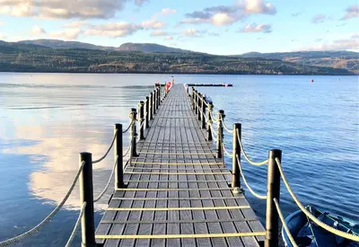 a dock on a body of water with a boat at Glenbranter Cottage in Strachur