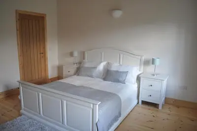 a bedroom with a white bed with two night stands at The Old Stables, Alltshellach Cottages in North Ballachulish