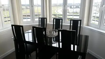 a dining room with a table and chairs and windows at Crystal Apartments in Airdrie