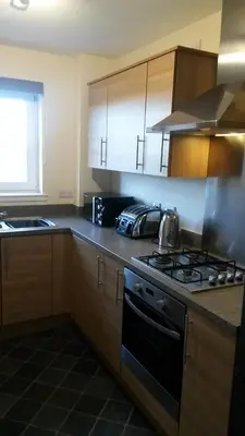 a kitchen with wooden cabinets and a stove top oven at Crystal Apartments in Airdrie
