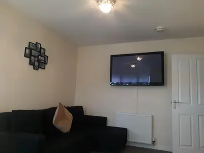 a living room with a black couch and a flat screen tv at Crystal Apartments in Airdrie