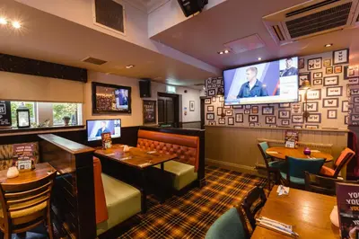 a restaurant with tables and a flat screen tv at The Abbey Inn in Paisley