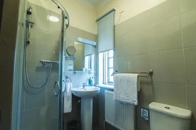 a bathroom with a shower and a sink and a toilet at The Abbey Inn in Paisley