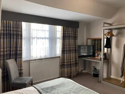 a bedroom with a bed and a desk and a window at Tullie Inn in Balloch