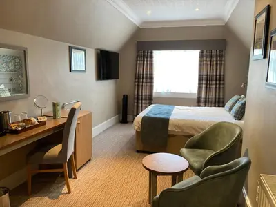 a hotel room with a bed and a desk and chairs at Tullie Inn in Balloch