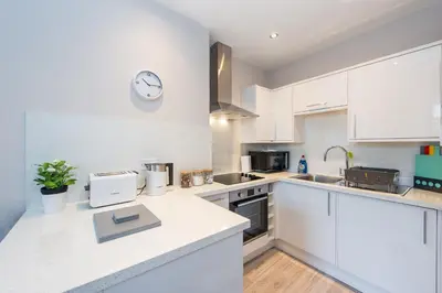 a kitchen with white cabinets and a clock on the wall at The New Westfield in Edinburgh