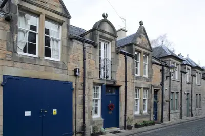 a row of buildings with blue doors on a street at Quiet Ground Floor Mews Flat and parking in Edinburgh