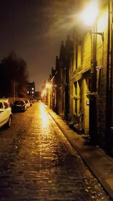 a cobblestone street at night with cars parked at Quiet Ground Floor Mews Flat and parking in Edinburgh